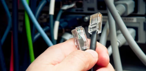 a person holdin a lan cable while managing network cables